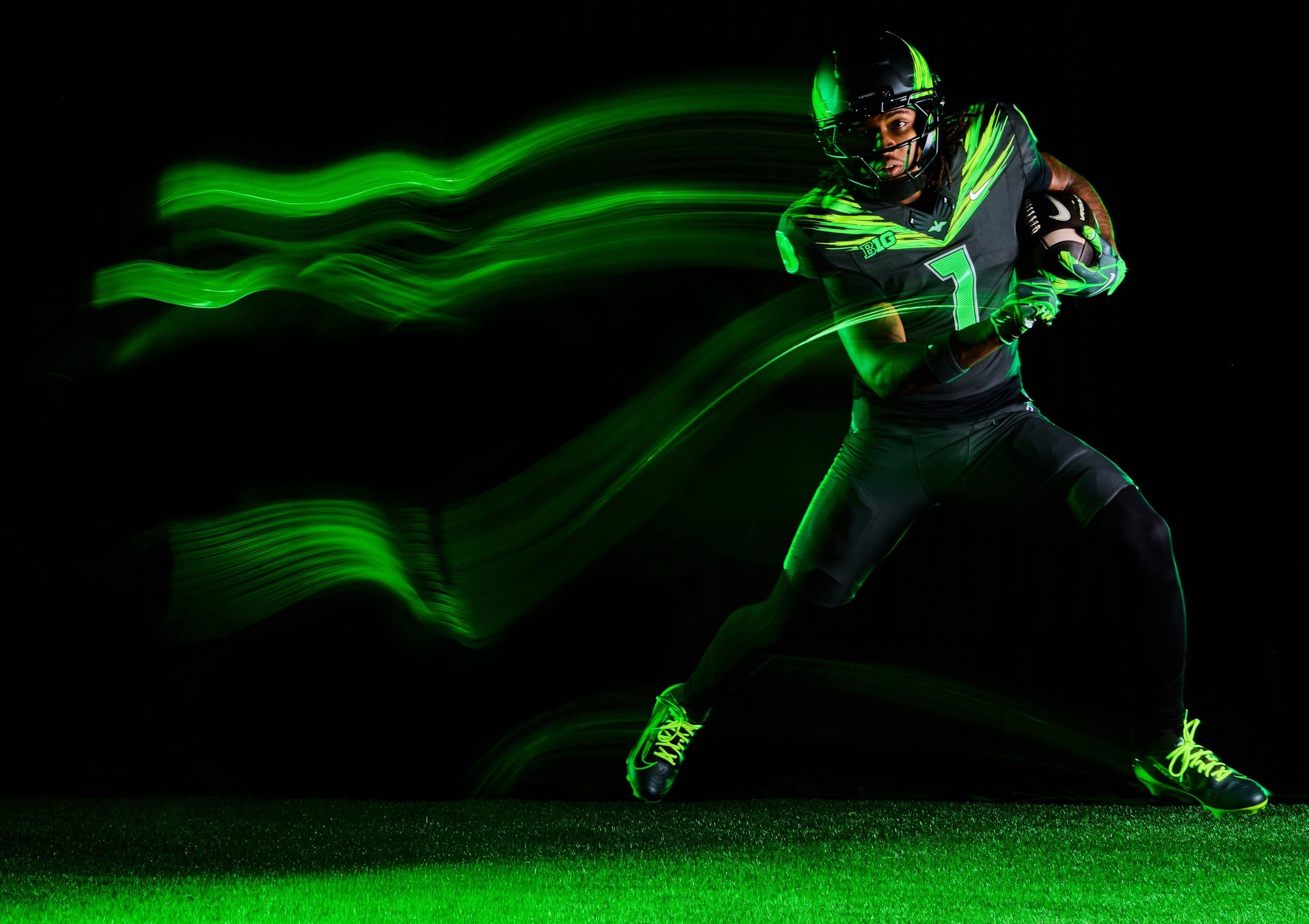 Uniforme da football americano verde scuro e giallo fluo con dettagli riflettenti argento su sfondo neutro scuro, stile editoriale